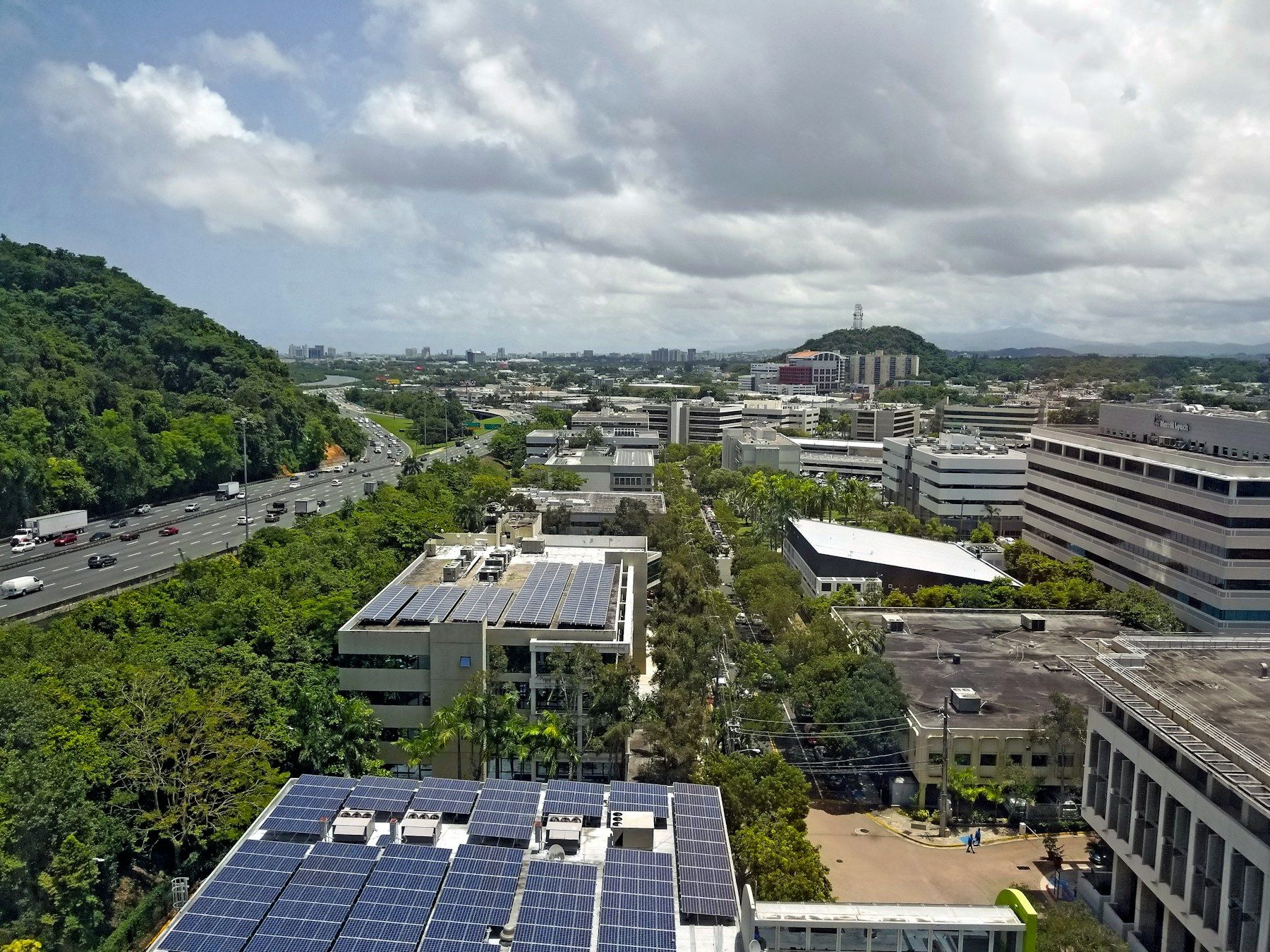 Vista aérea de Guaynabo, Puerto Rico, con paneles solares sobre techos de edificios y montañas al fondo